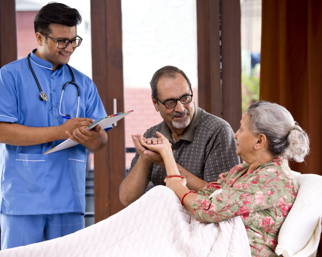 Male nurse making a note of senior patient at home